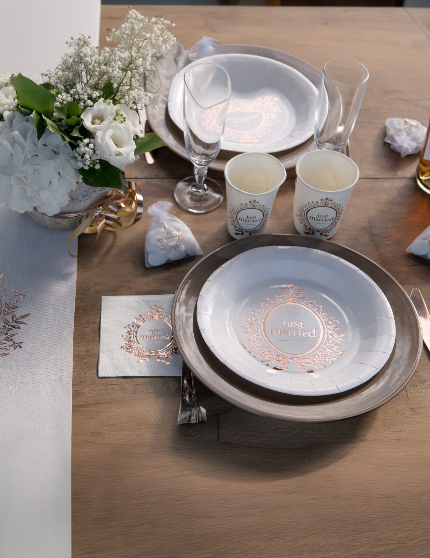 Vue d'ensemble de la décoration de table des assiettes en carton Just Married pour mariage chic blanches et rose gold