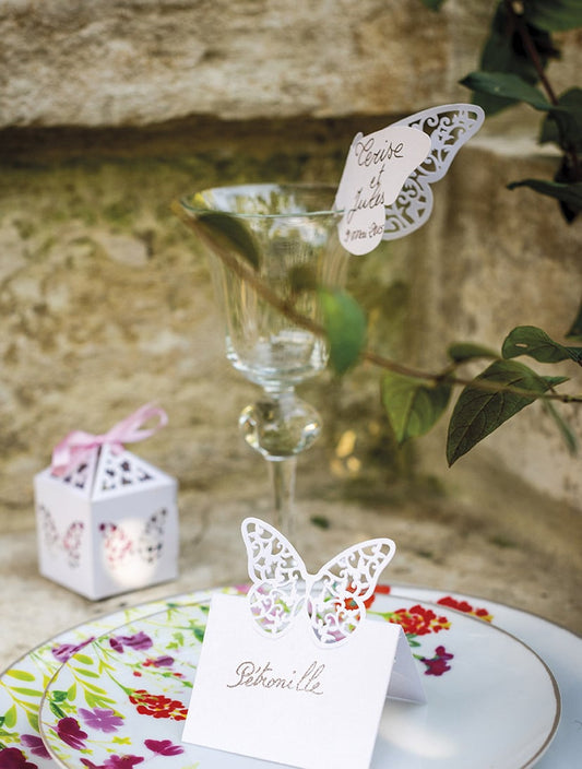 Mise en scène sur une table de fête du marque-places papillons dentelles