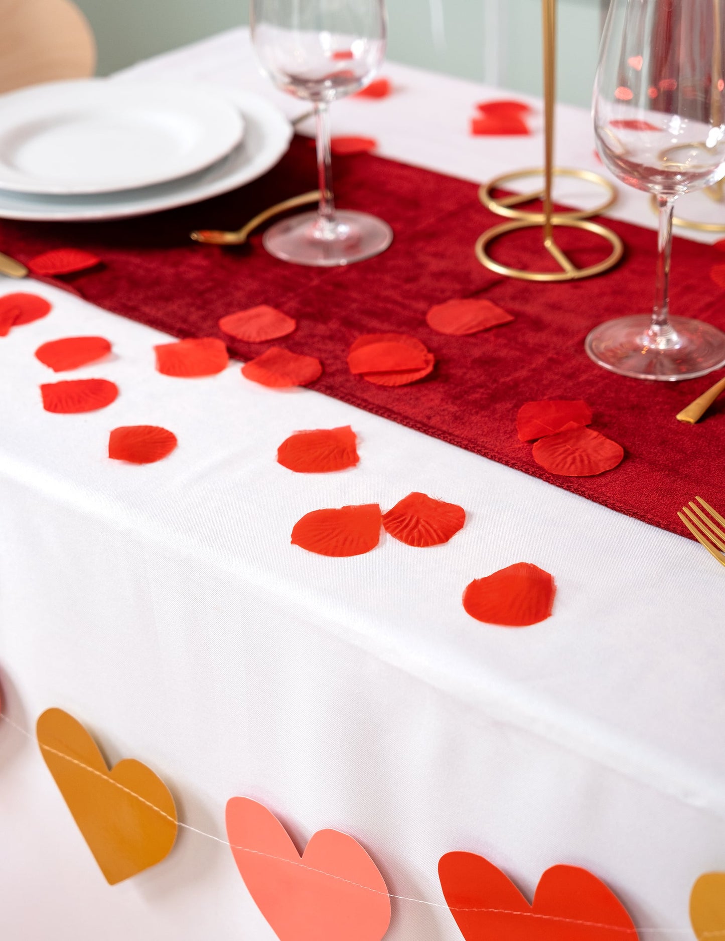 Mise en situation sur une table des pétales de rose en tissu pour fête rouge