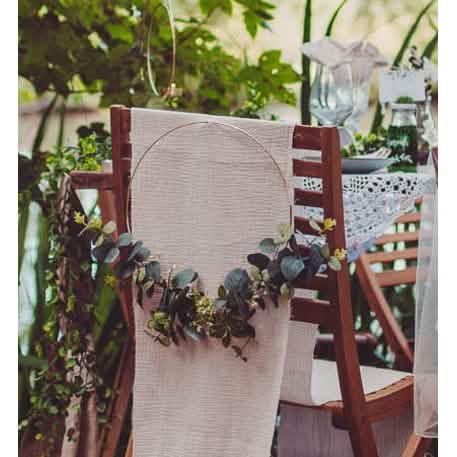 Mise en situation sur un dossier de chaise de la couronne en métal d'eucalyptus et fleurs blanches cercle or