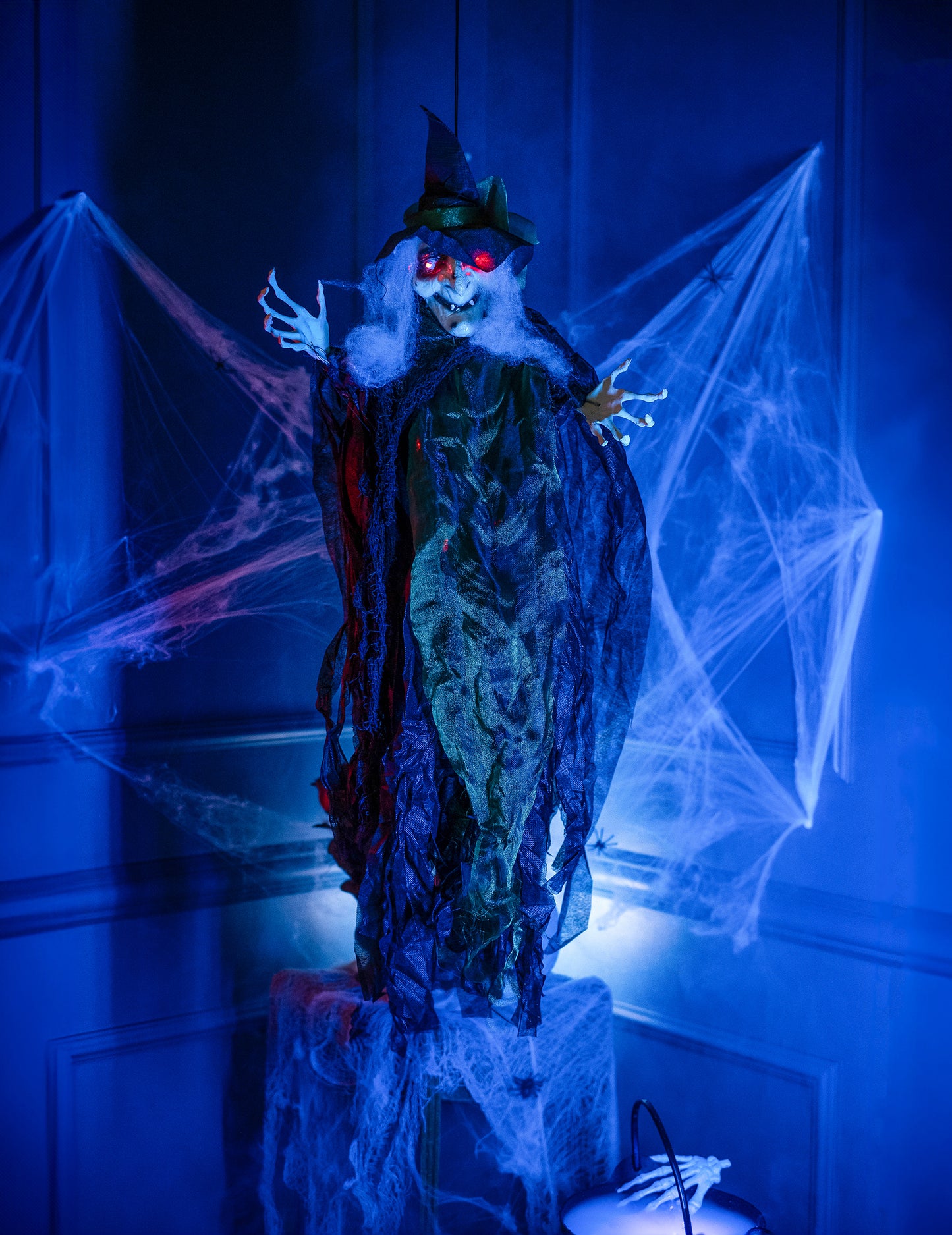 Mise en situation dans un décor d'Halloween de la décoration à suspendre sorcière lumineuse