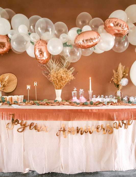 Mise en situation sur une table d'anniversaire du kit arche de 70 ballons rose gold avec eucalyptus et roses