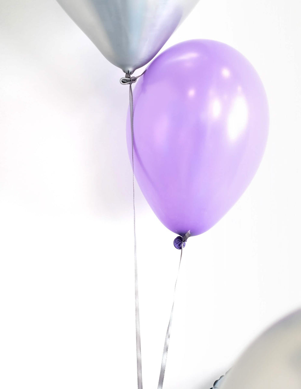 Großaufnahme der Luftballons mit Bändern von metallisierten Party-Luftballons zur Dekoration in Fliederfarben