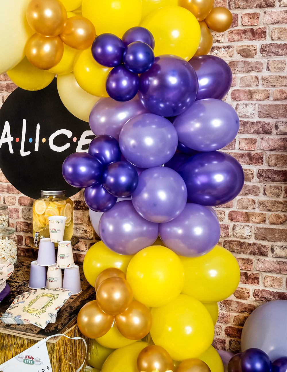 Szenenaufbau mit violetten metallisierten Luftballons in Bogenform für die Party
