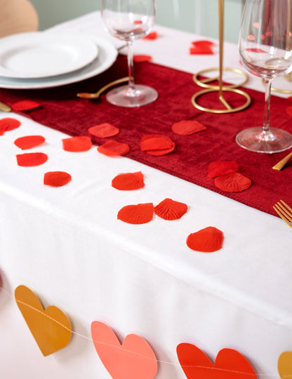 Mise en situation sur une table des pétales de rose en tissu pour fête rouge