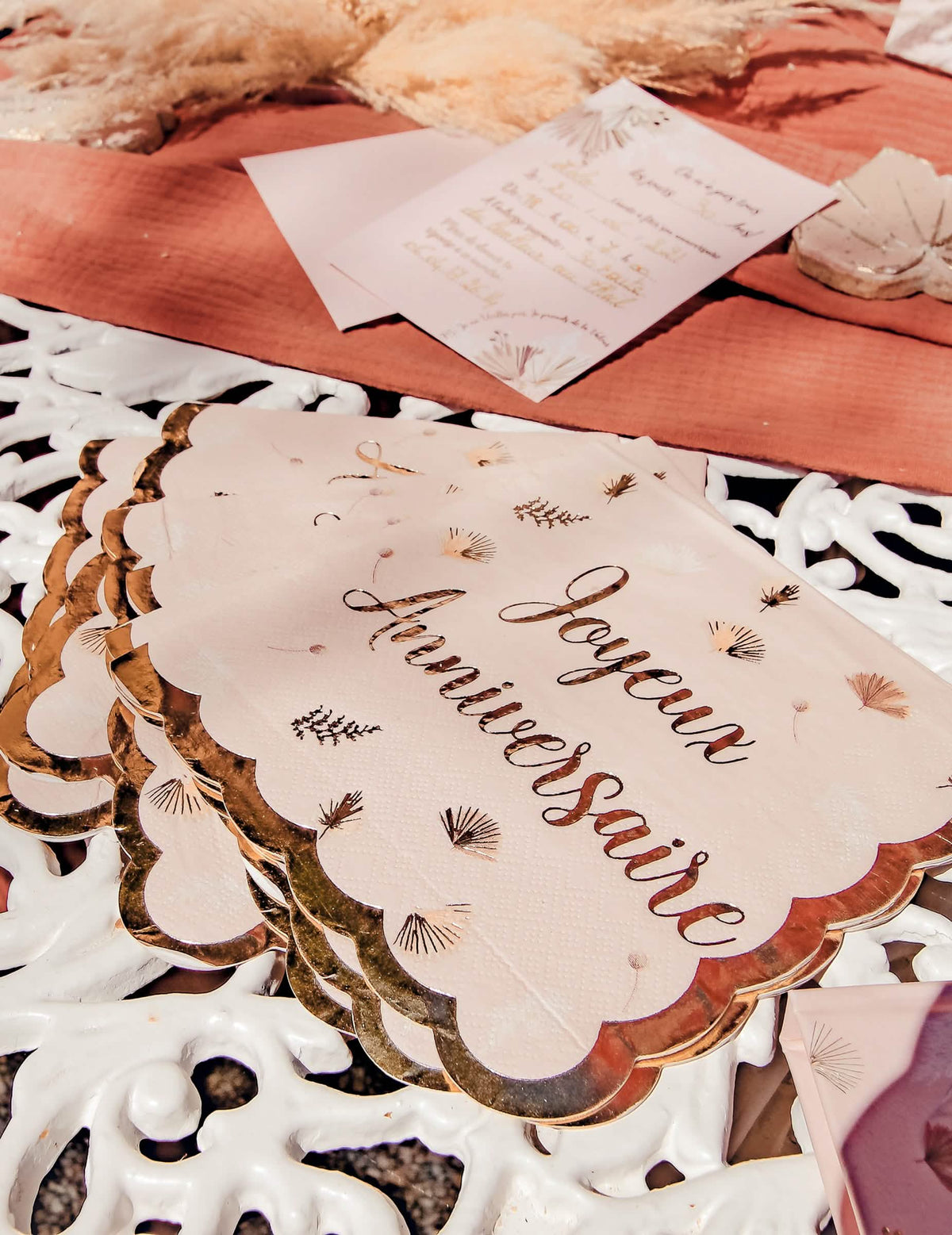 Détail de l'écriture et des bords dorés des serviettes joyeux anniversaire boho blush et or festonnées