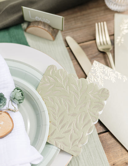 Détail de la décoration de table avec les serviettes cocktail en papier à bords festonnés pour fête vert sauge et or