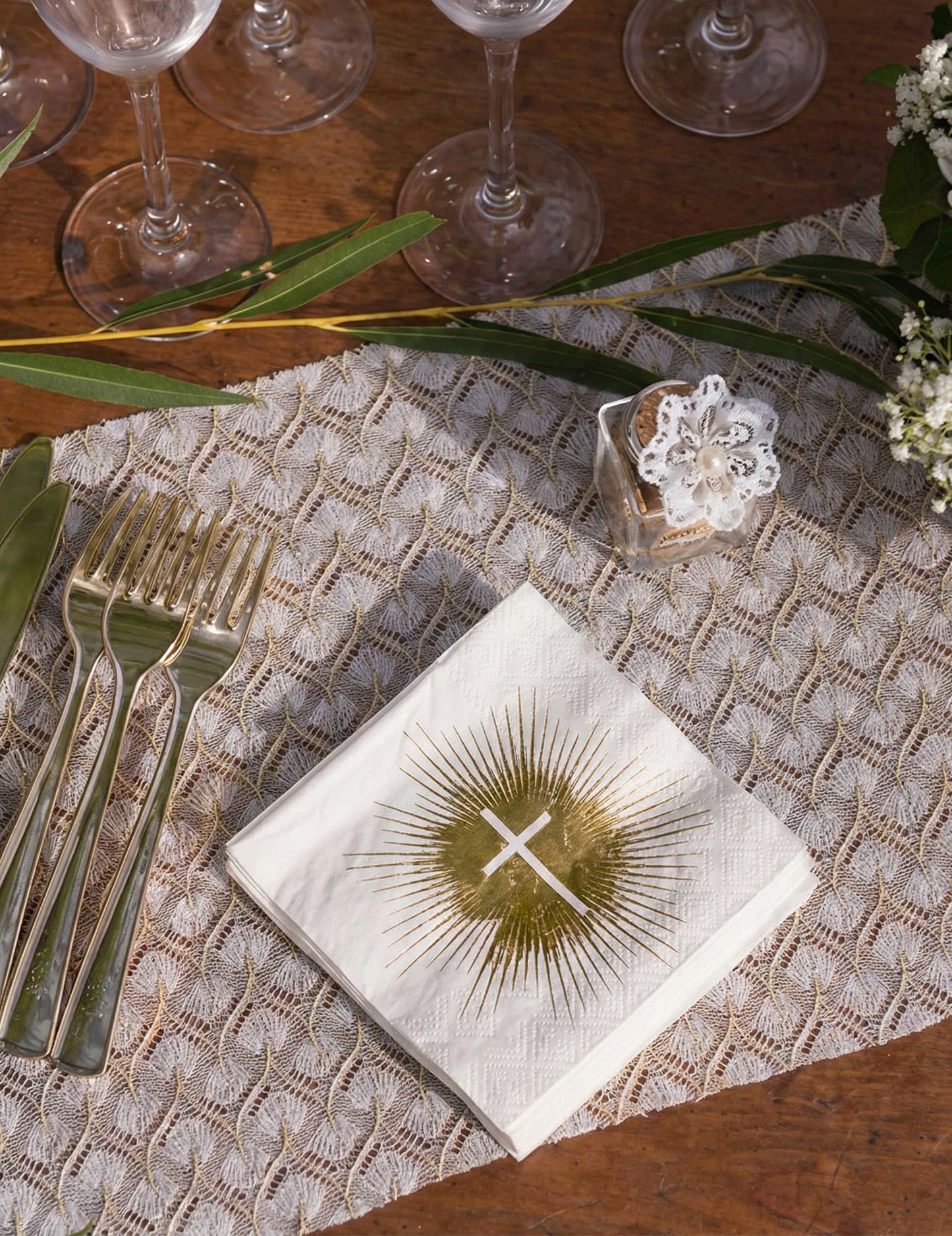 Mise en situation sur une table des serviettes papier cérémonie croix blanche et dorée