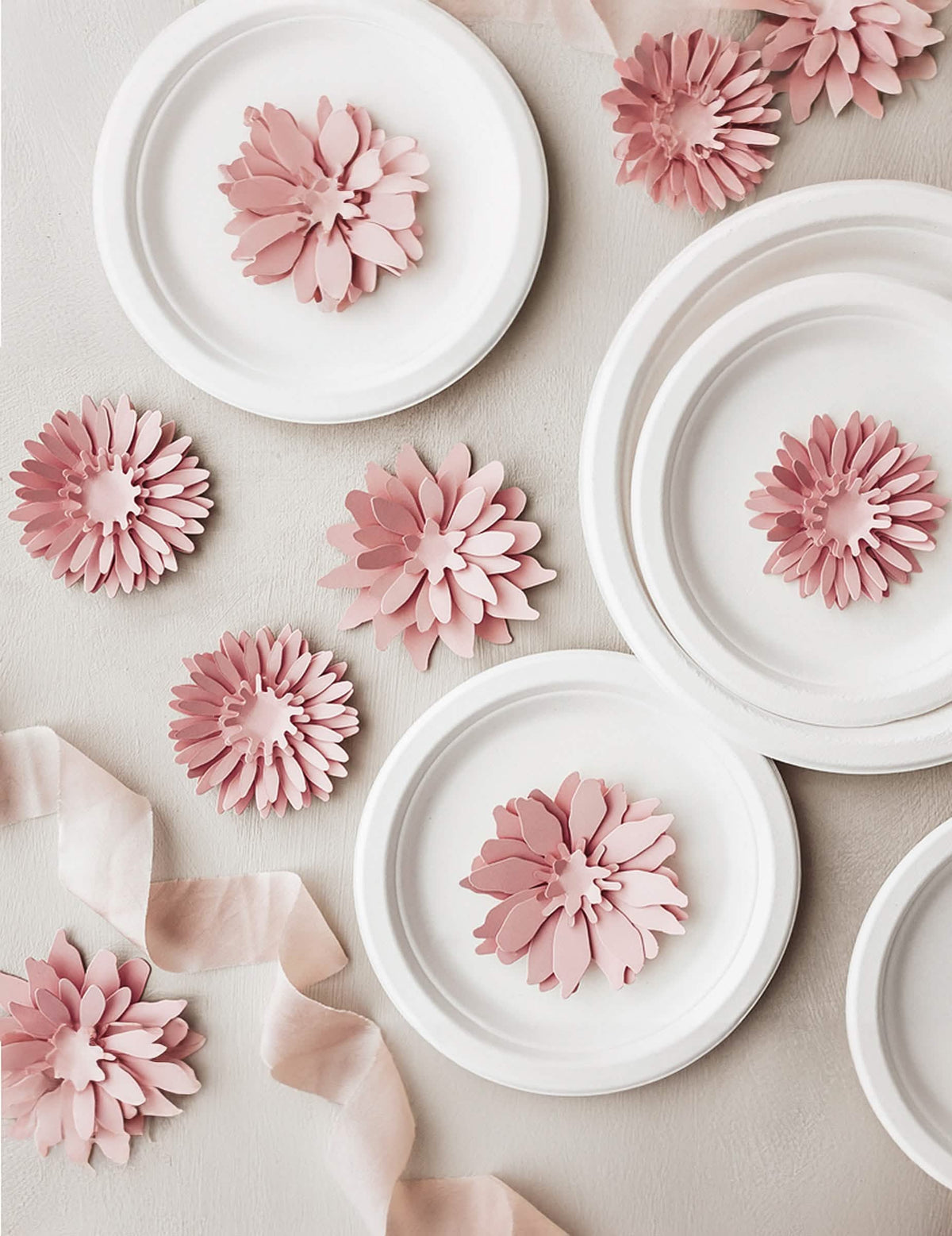 Mise en scène sur des assiettes des fleurs en papier 3D pour décoration rose poudré