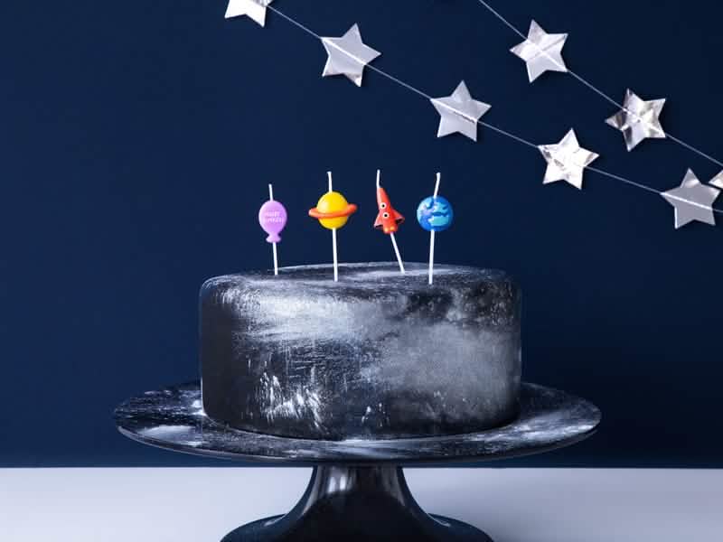 Mise en situation sur un gâteau des 4 bougies d'anniversaire astronaute fusée et planète