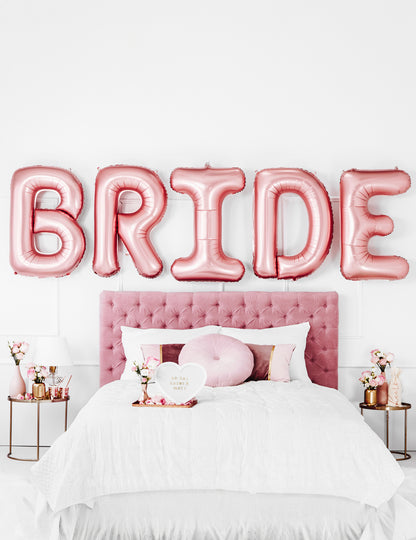 Mise en scène au-dessus d'un lit des ballons lettres Bride pour EVJF rose gold