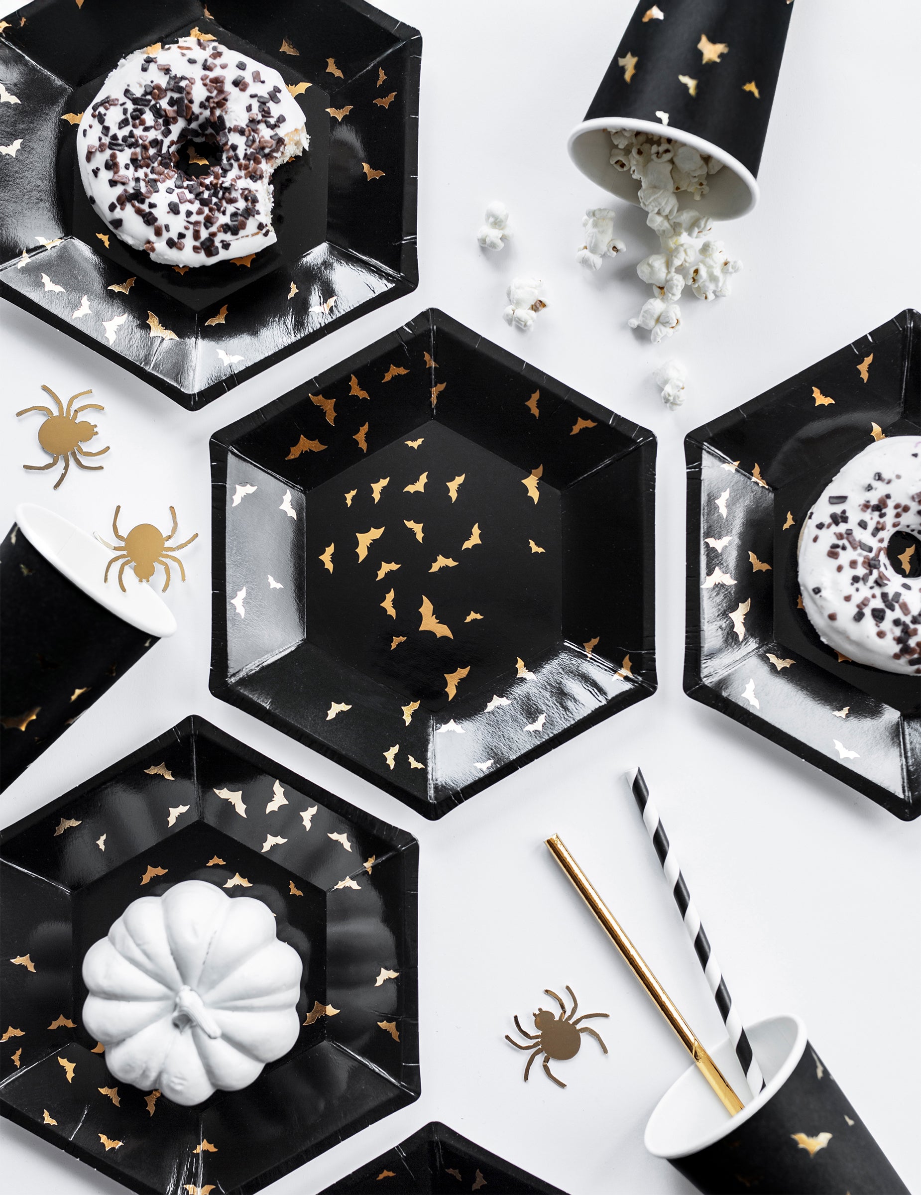 Mise en situation avec décorations de table des assiettes en carton chauves-souris noires et dorées hexagonales
