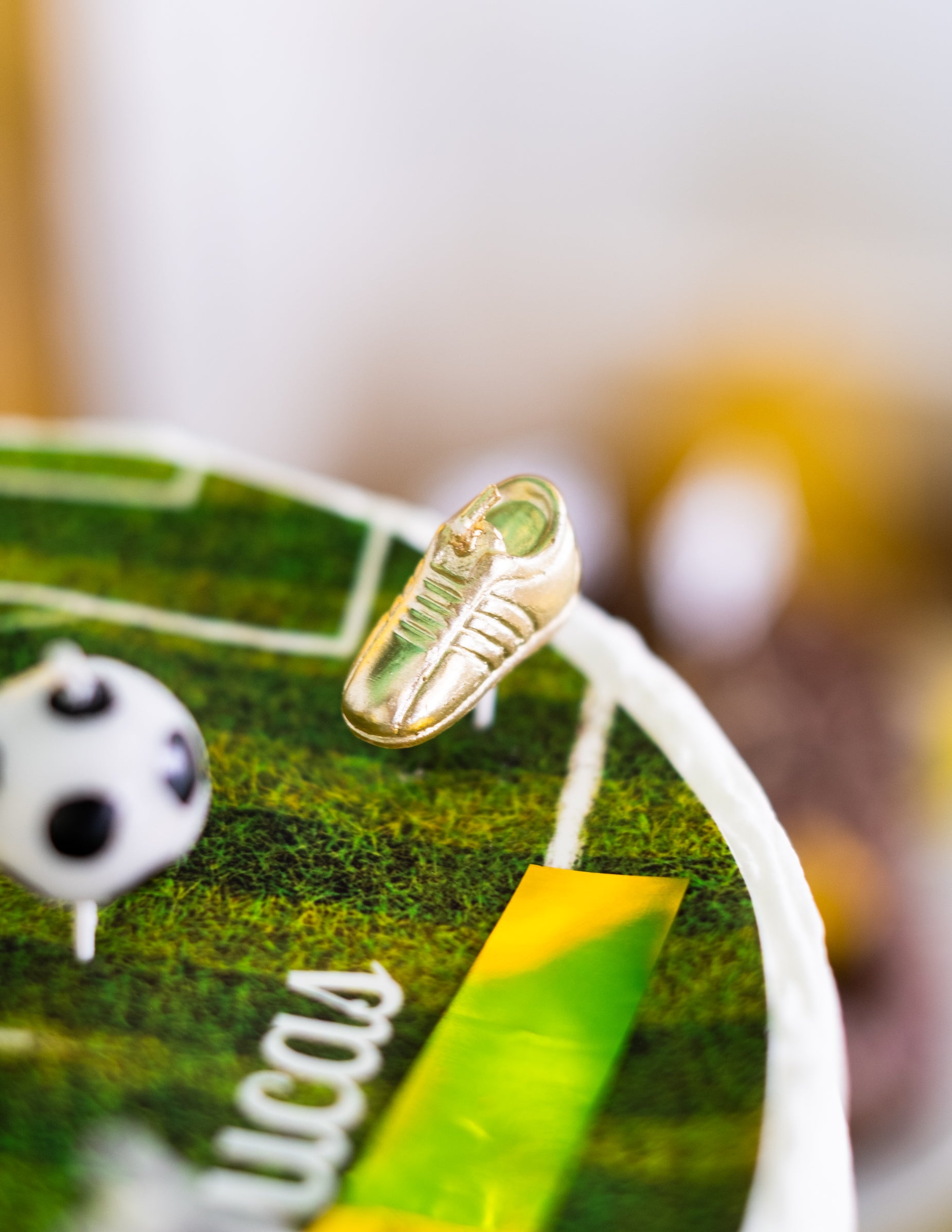 Gros plan sur la bougie chaussure dorée du lot de 6 bougies ballons et chaussures de foot