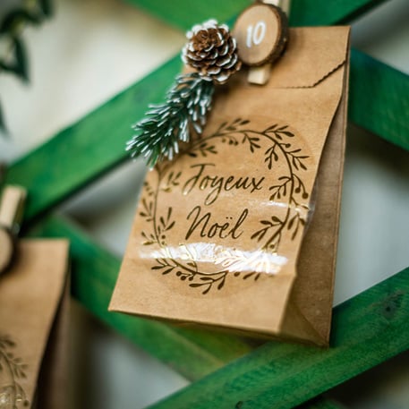 Gros plan sur le sachet Joyeux Noël des petits sachets kraft pour invités marron avec étiquettes et ficelles blanches