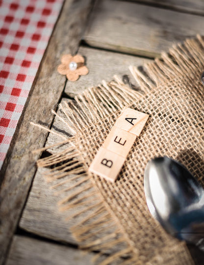 Mise en situation sur de la toile de jute des 60 lettres alphabet façon scrabble pour décoration de table en bois