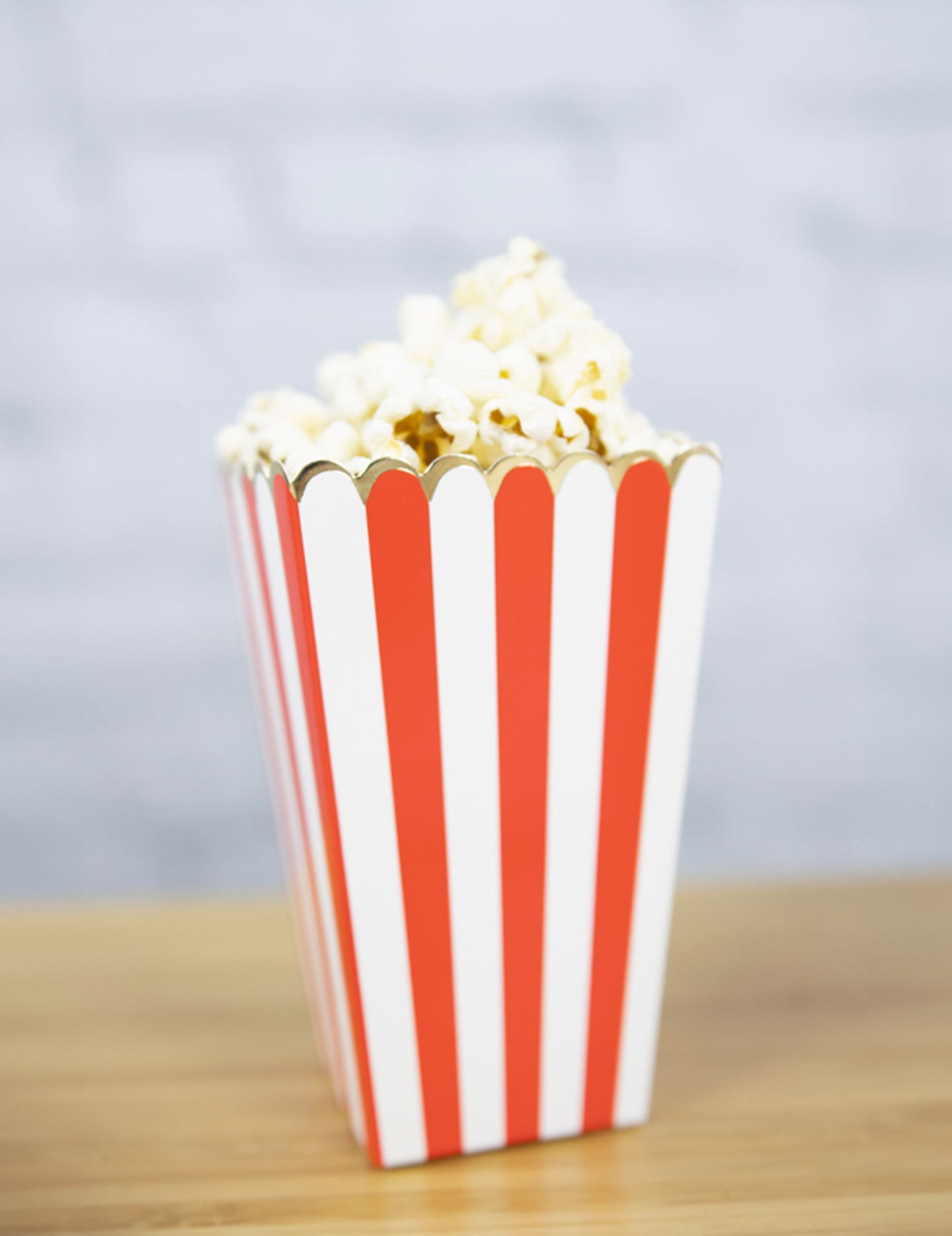 Vue d'une boîte remplie de popcorn des boîtes à popcorn à rayures pour fête rouges et blanches avec liseré doré