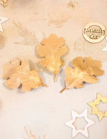 Mise en situation de trois feuilles de chêne en tissu métallisé pour décoration dorées