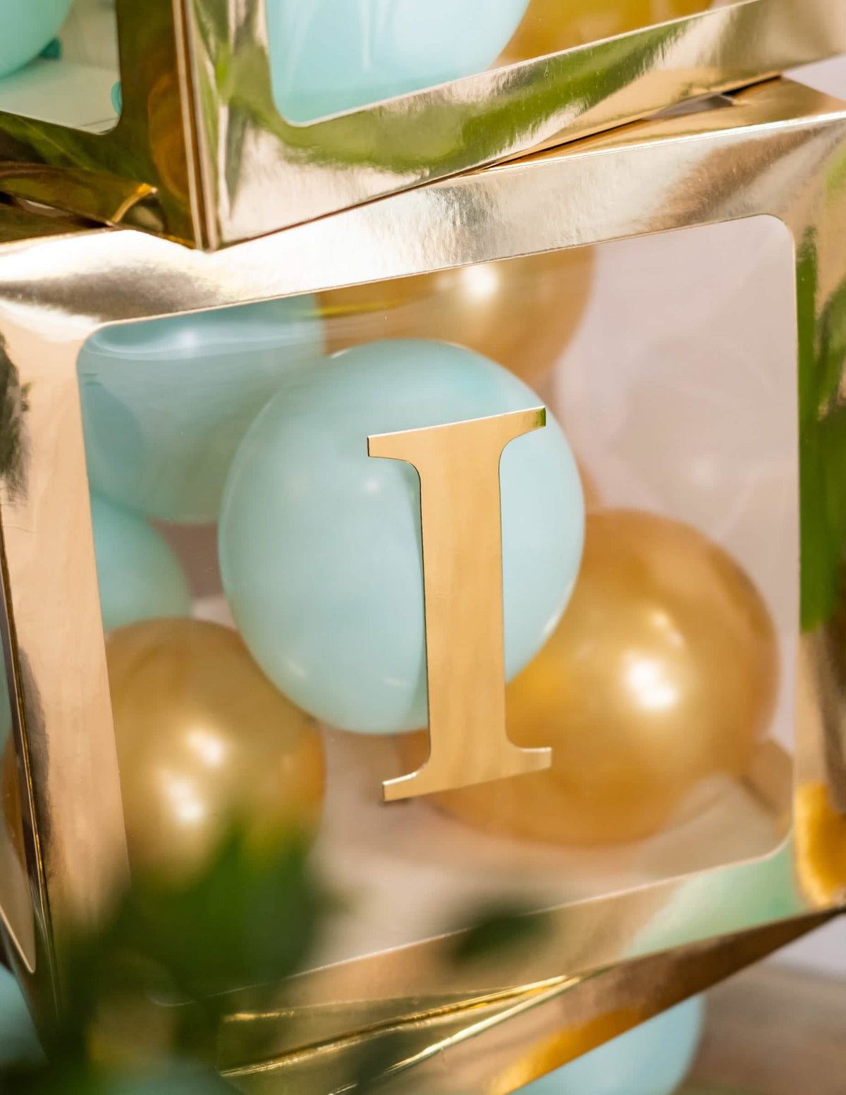 Gros plan sur la lettre I du cube à ballons transparent pour fête doré personnalisable