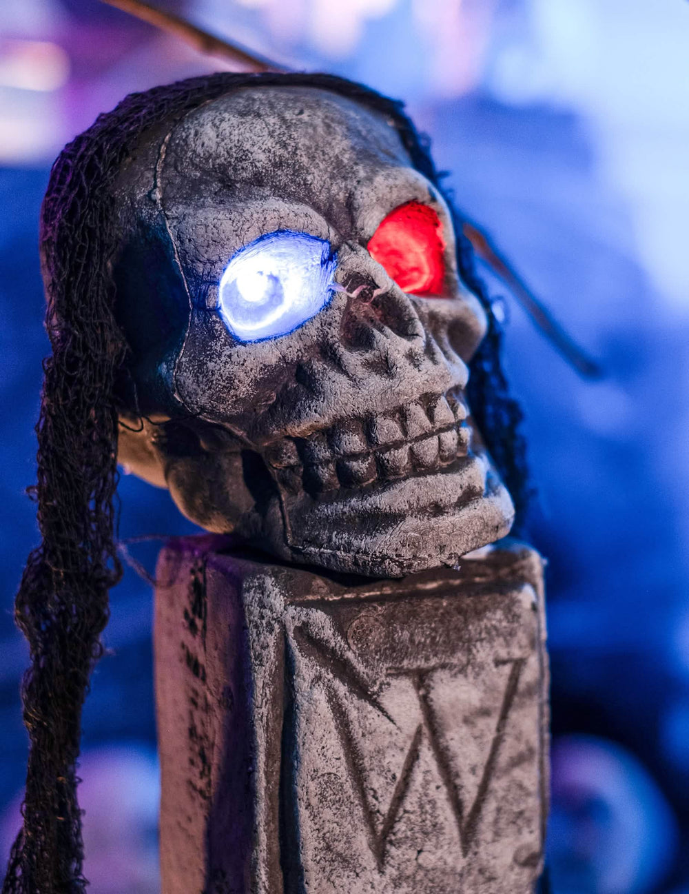 Nahaufnahme des Totenkopfs mit LED-Augen der leuchtenden Schaufensterdekoration Grab Halloween
