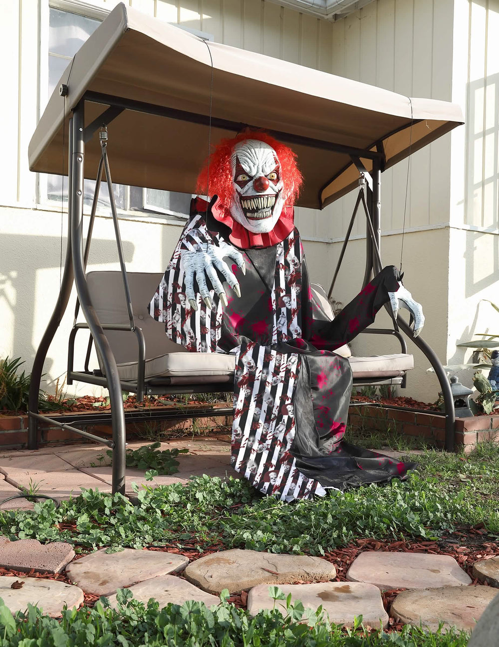Sitzender Clown auf einer Schaukel des riesigen gruseligen Clownkostüms 2 in 1