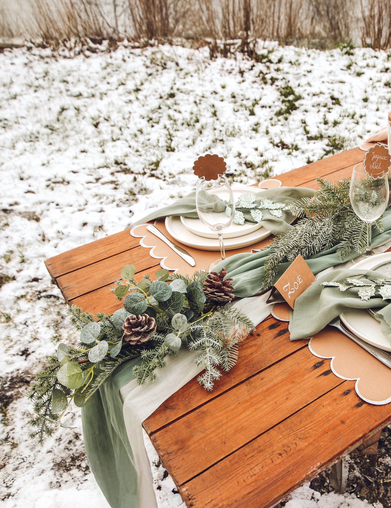 Mise en scène sur une table de fête de la descente de sapin et eucalyptus avec pommes de pin