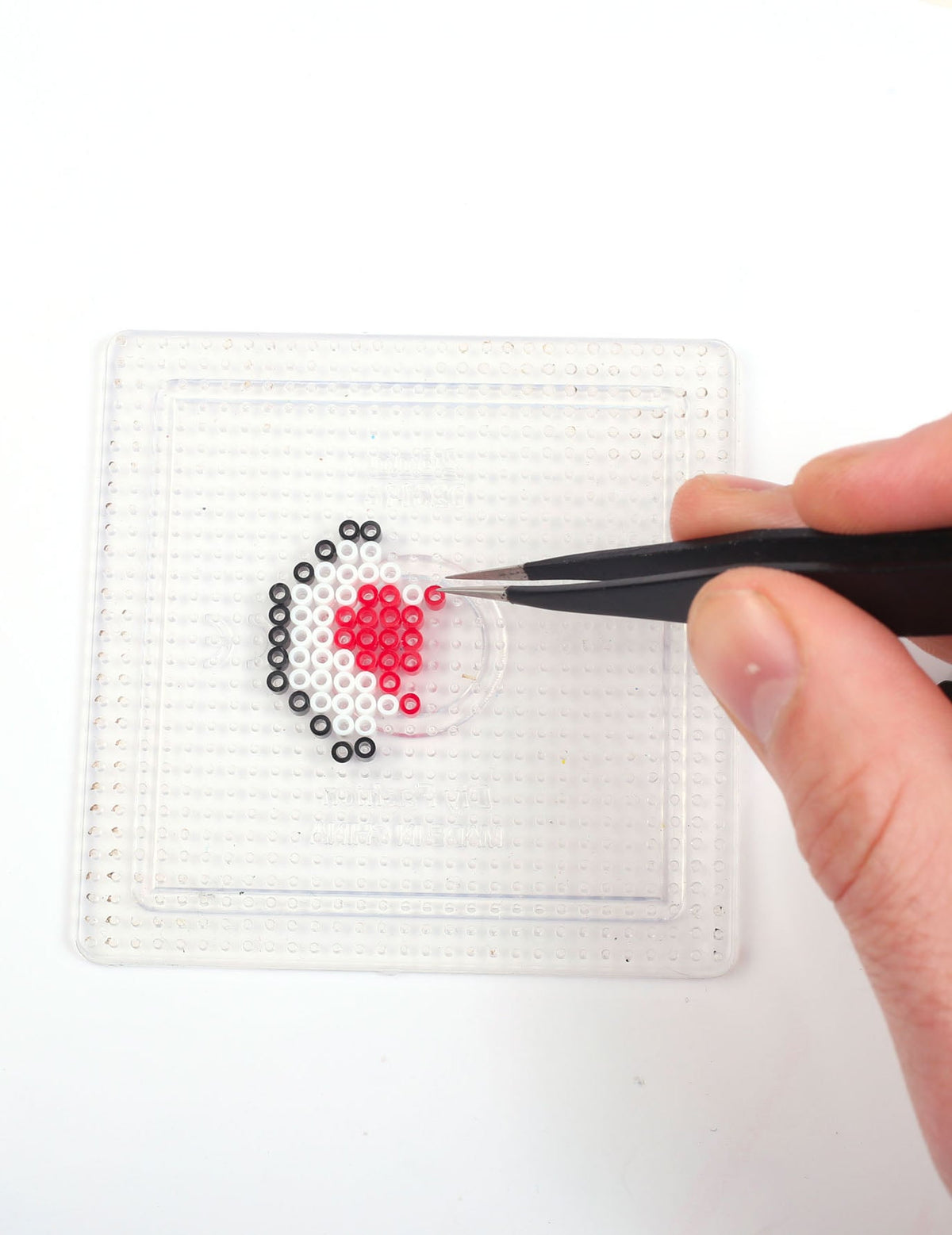 Détail du placement des perles avec une pince du Kit perles à repasser Père Noël