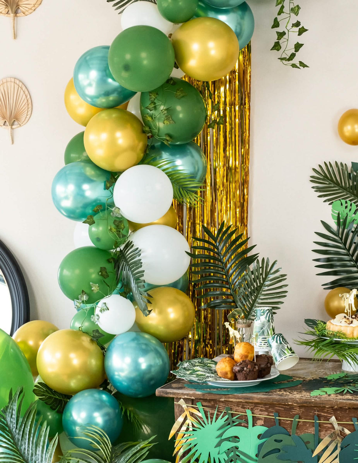 Arche de ballons tropicale devant le rideau scintillant pour décoration de fête or